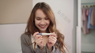 快乐女人持有积极的怀孕测试女孕妇婴儿出生等待